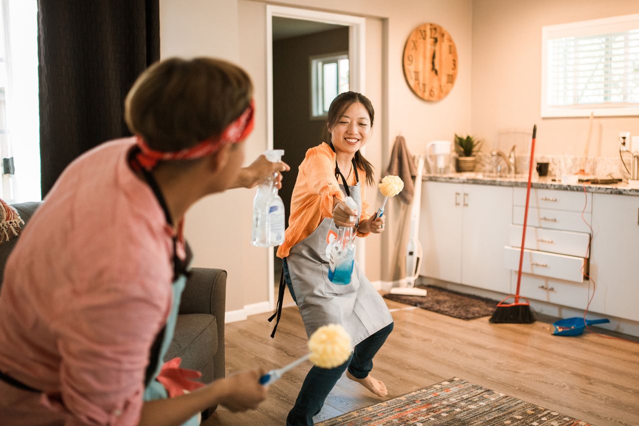 hero-01 Asian couple having fun while cleaning their home, enhancing a cheerful atmosphere.
